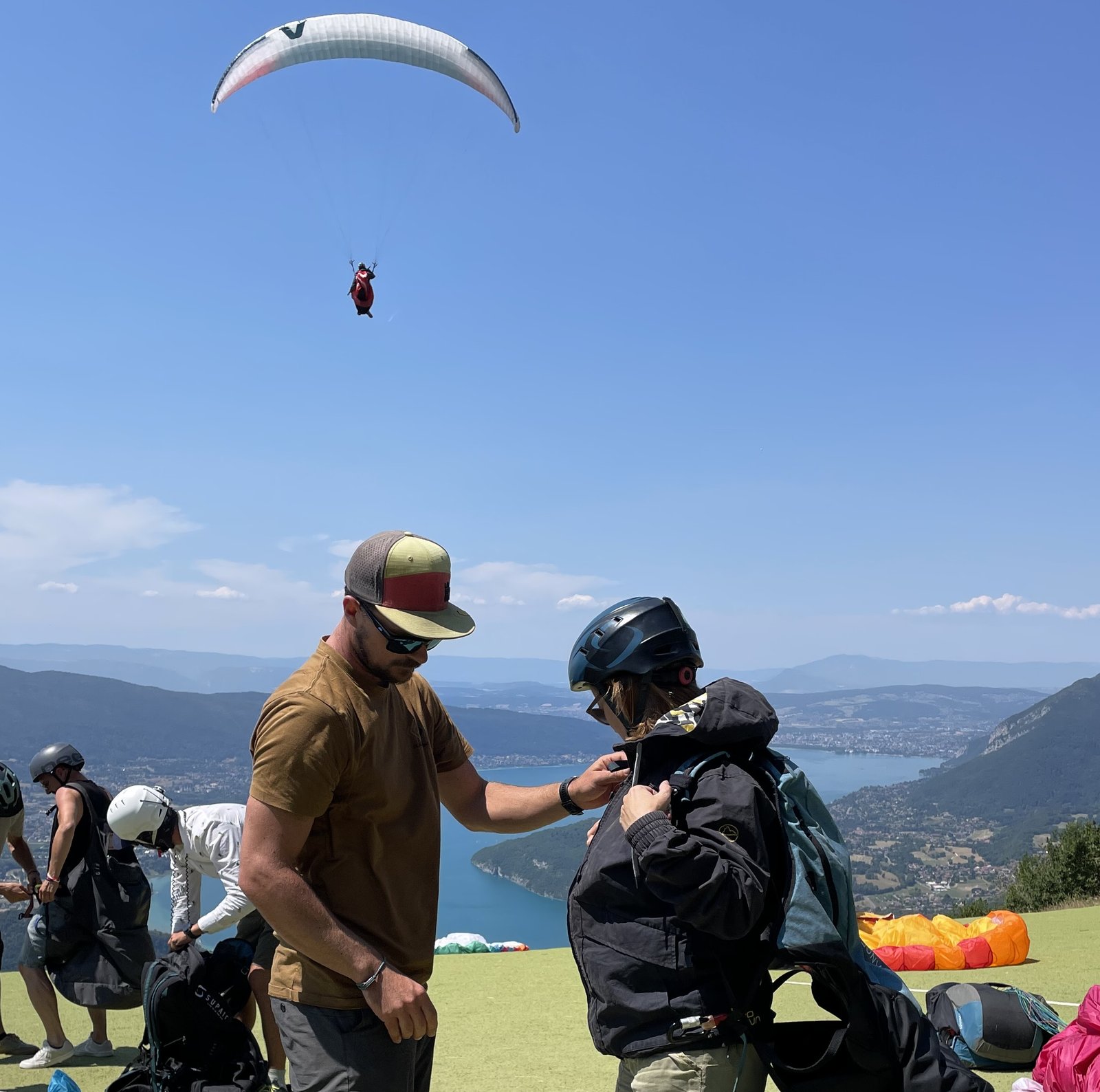 Martin, moniteur de parapente, ajuste l’équipement d’une passagère avant un décollage en biplace